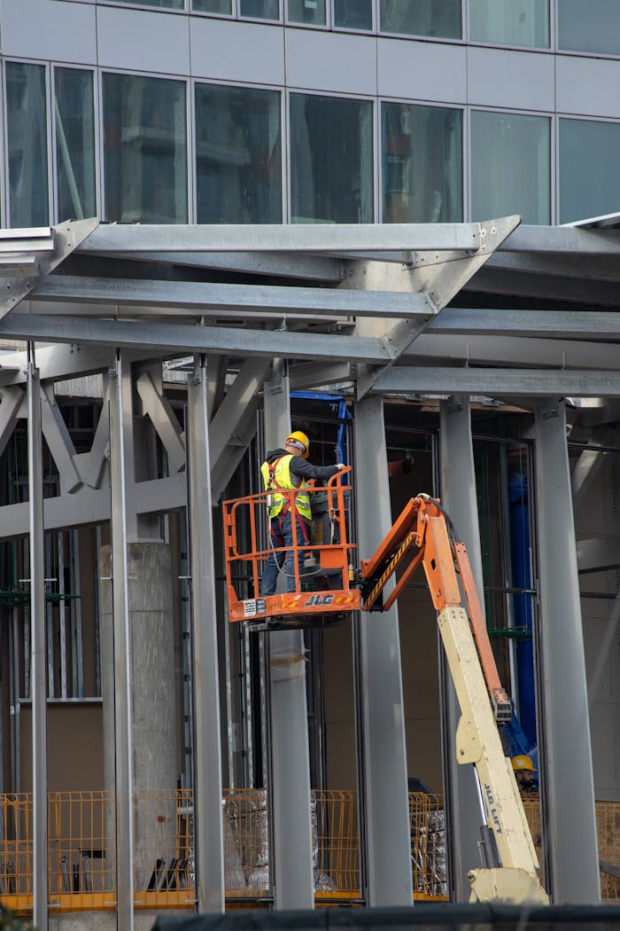 Construction worker operating aerial lift during urban building project with steel structures.